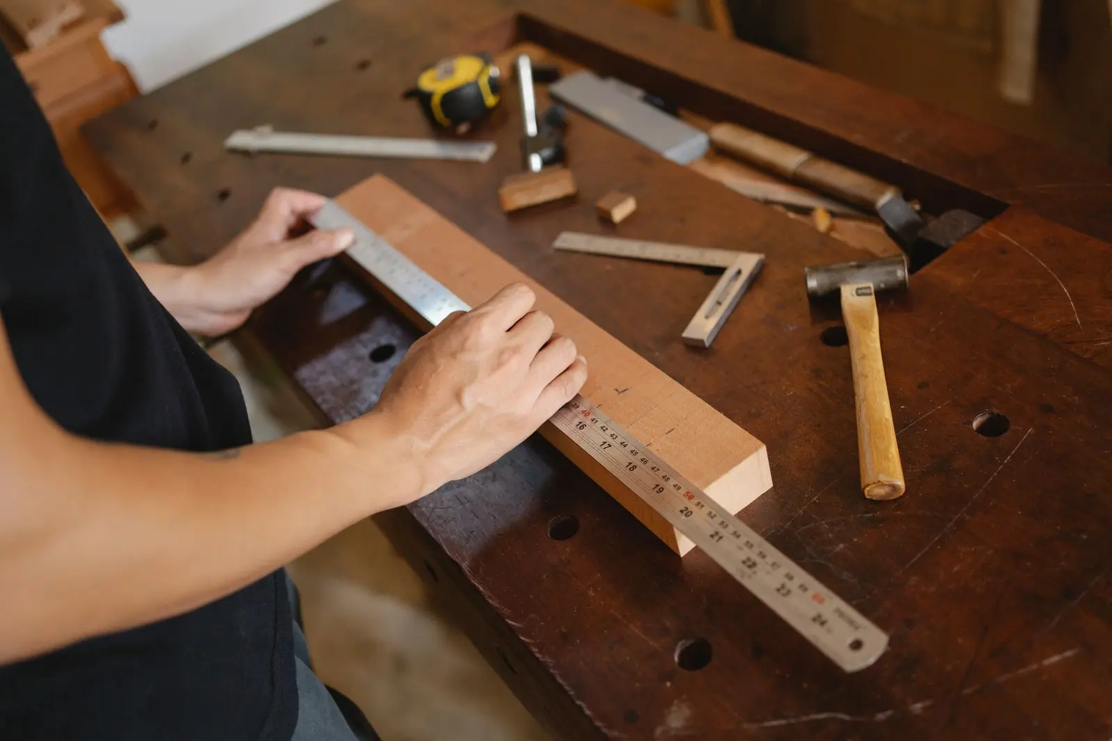 Manos midiendo una tabla de madera con una regla